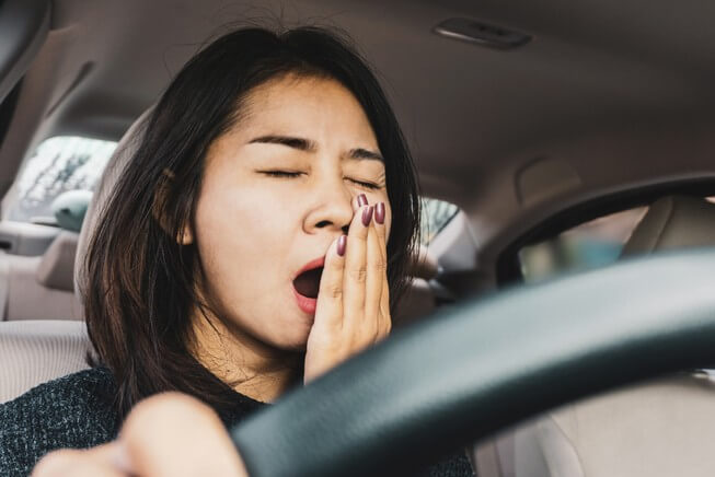 Sleepy woman yawns while driving