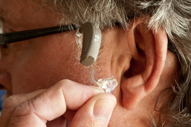 Man with hearing loss gets hearing aid inserted into ear 