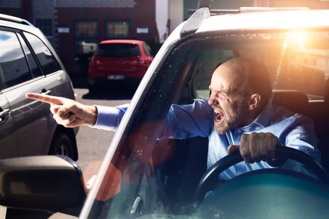Man aggressively yells and points finger at another vehicle while driving