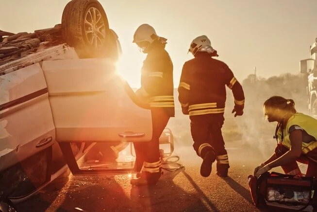 Paramedics and firefighters rescue man trapped in car from a rollover car accident