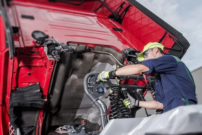 Man performancing maintenance on tractor trailer