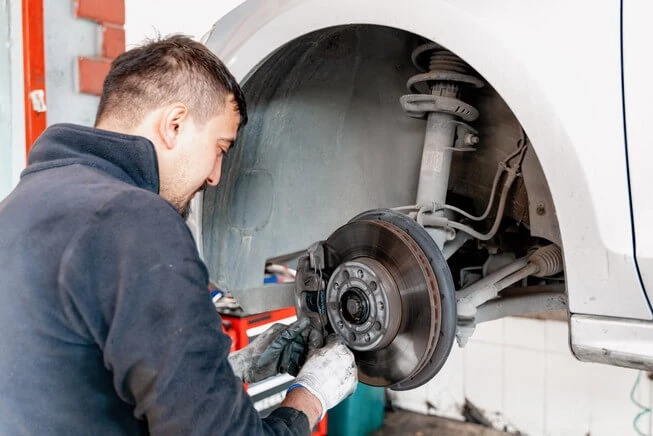 Car mechanic replacing braces on car